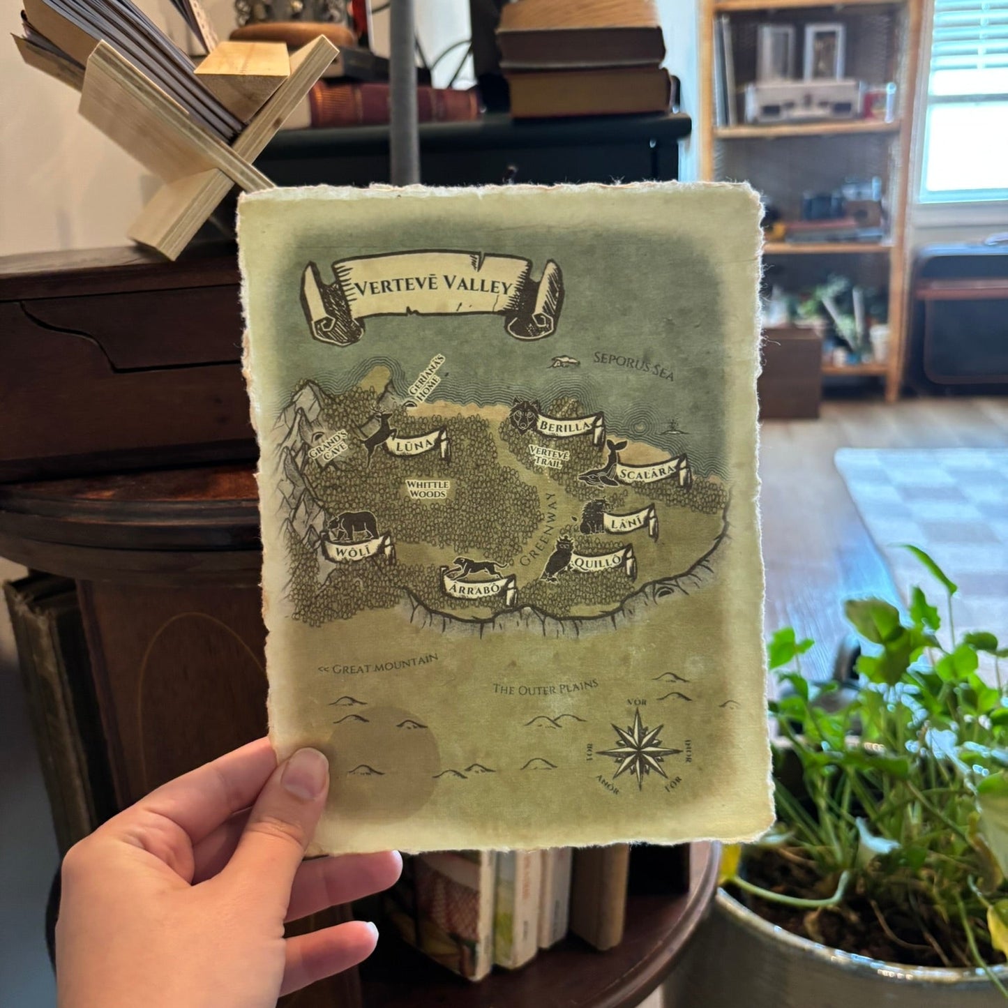 Hand holding a map of Verteve Valley against a blurred indoor background