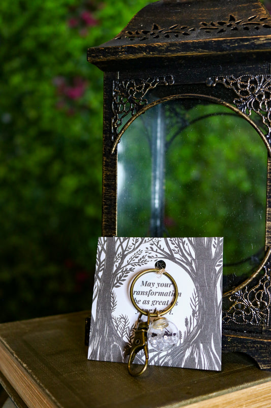 Decorative lantern with a card featuring a nature-themed design on a wooden surface.